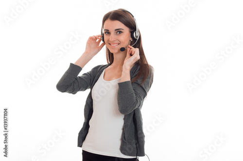 beautiful young girl in headphones and gray jacket turned aside and keeps hands the microphone near the face