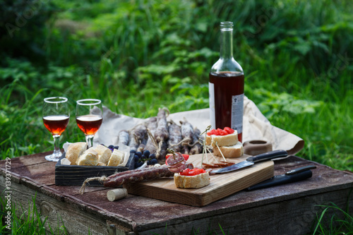 Sausage, tomato, bread and a glasses of red wine, contryside.