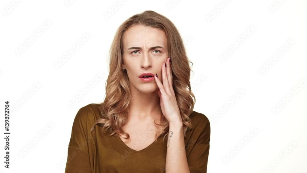 Tired beautiful middle-aged Caucasian female with long brown hair standing on white background with headache in slowmotion Tired beautiful middle-aged Caucasian female with long brown hair standing on white background with headache in slowmotion