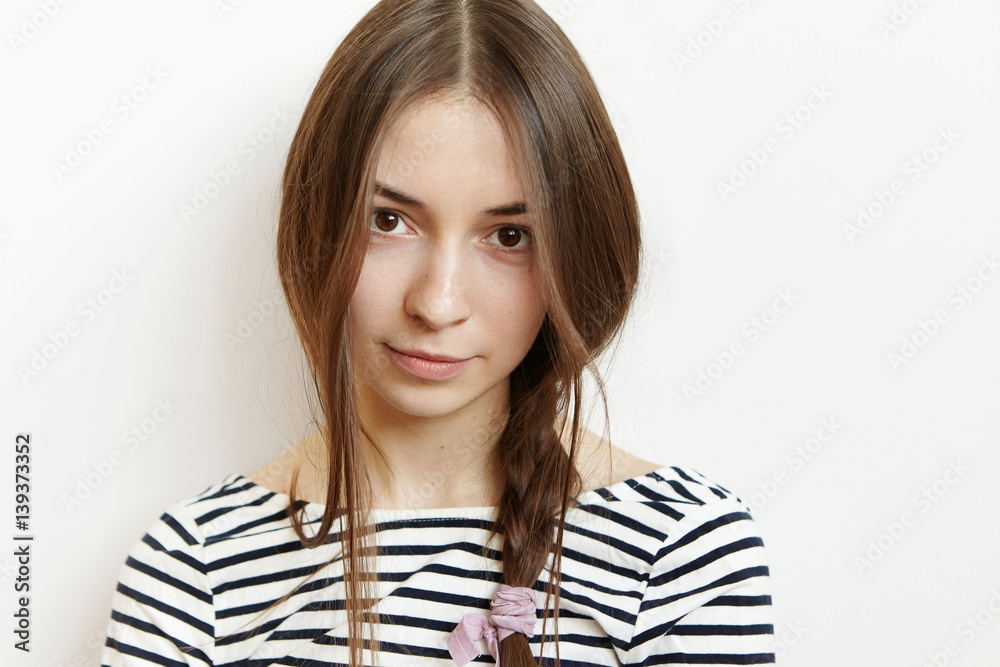 Beautiful teenage girl with healthy perfect skin and dark hair posing isolated against studio wall background. Headshot of young Caucasian brunette woman dressed in striped black and white top Beautiful teenage girl with healthy perfect skin and dark hair posing isolated against studio wall background. Headshot of young Caucasian brunette woman dressed in striped black and white top