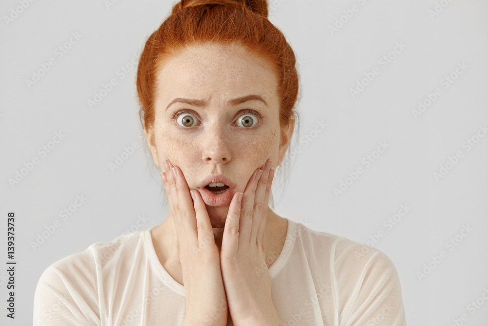 Omg! Headshot of funny bug-eyed girl with ginger hair keeping hands on  cheeks, having shocked or frightened look, having forgot to do something  important. Human face expressions and emotions Photos | Adobe