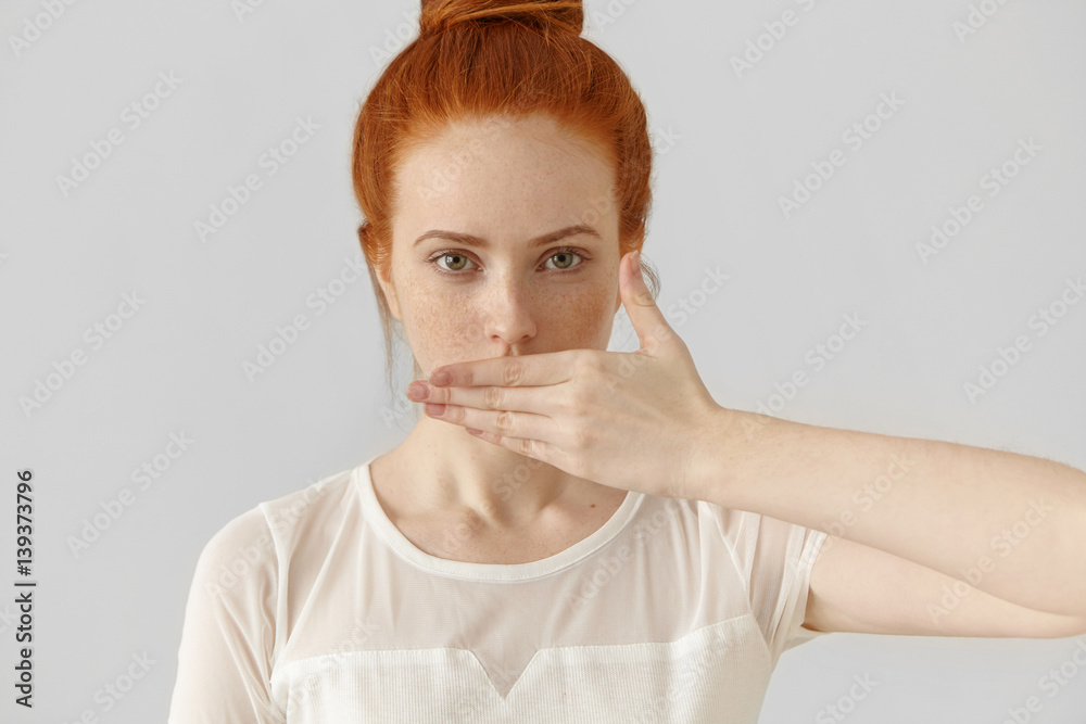 Φωτογραφία Portrait of attractive young redhead woman covering mouth with hand, keeping sec