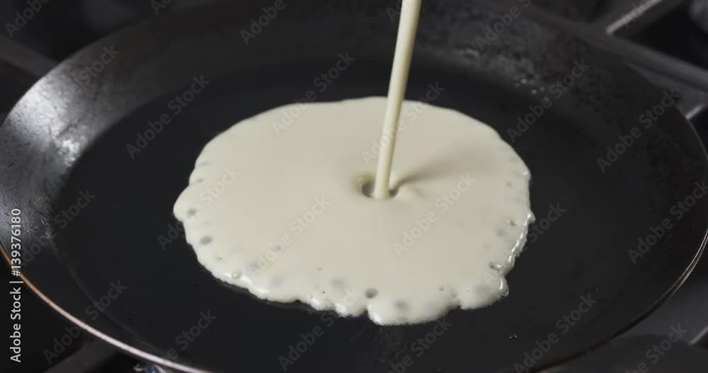 Slow motion of preparin blini or crepes batter pouring on hot pan, 4k 60fps prores footage