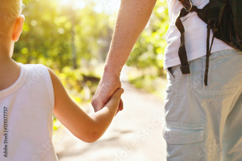 Obraz na plátně child holding hand of adult parent outside in summer park