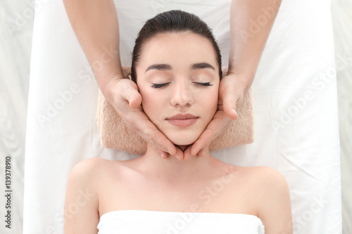 Beautiful young woman receiving facial massage in spa salon