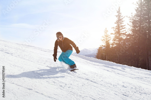 snowboard winter activity, snowboarder going downhill on the slope in mountains