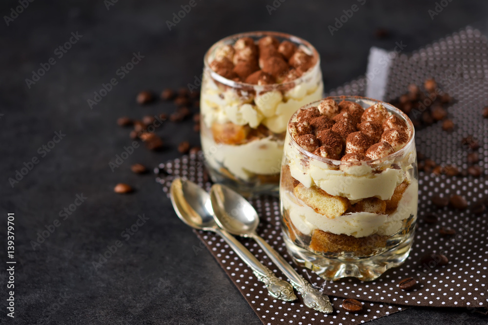 Classic tiramisu in a glass jar on a black background Classic tiramisu in a glass jar on a black background