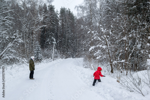 mother and daughter walking along the road in winter forest