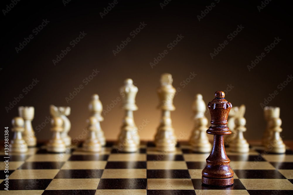 black chess queen in front of a chessboard, white chess pieces on a dark background black chess queen in front of a chessboard, white chess pieces on a dark background