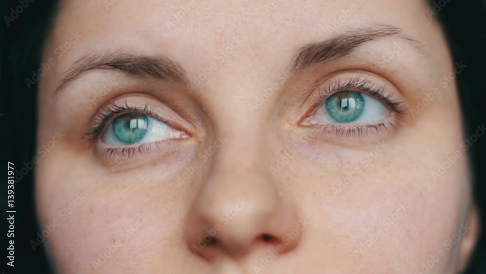 Green-eyed female face looks away and up to the camera. close-up view with sad girl Green-eyed female face looks away and up to the camera. close-up view with sad girl