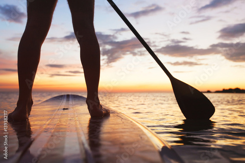 paddle board on the beach, close up of standing  legs and paddle photo