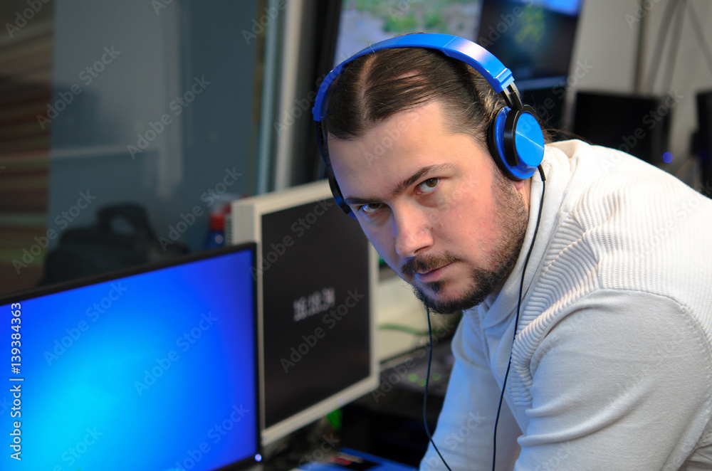 Video broadcast editor with headphones watching an action on the monitor. Live TV broadcasting process. Video broadcast editor with headphones watching an action on the monitor. Live TV broadcasting process.