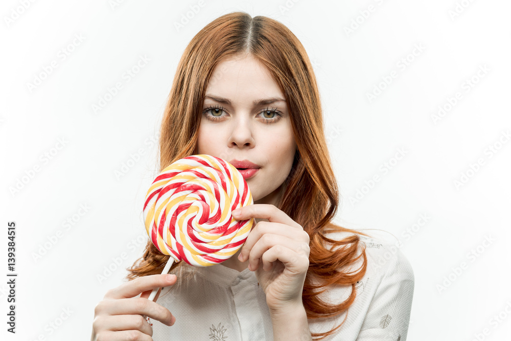 round multicolored lollipop in hand red-haired lady