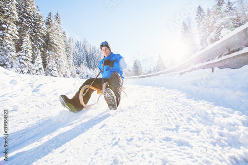 sleigh, winter holiday snow activity, young man having fun sledding