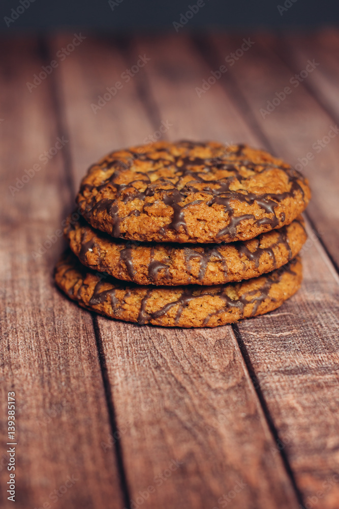 three cookies with chocolate icing on a wooden table three cookies with chocolate icing on a wooden table
