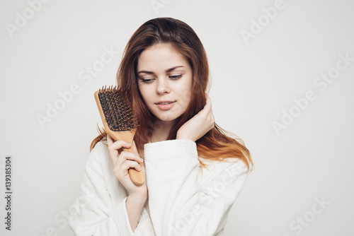 woman holding a wooden comb in her hand, long hair