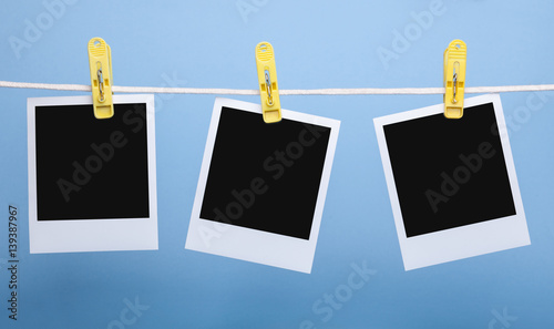 three blank insta photo frames on clothes pins on rope isolated on blue background