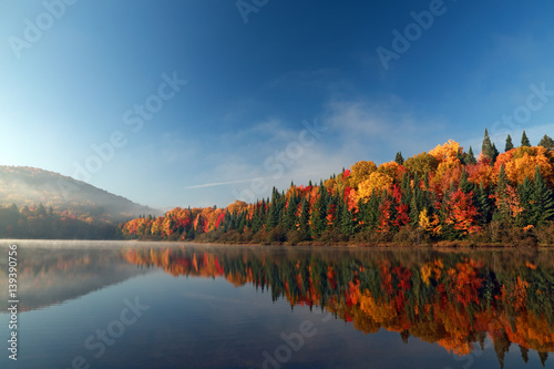 Autumn forest reflected in water. Colorful autumn morning in the mountains. Colourful autumn morning in mountain lake. Colorful autumn landscape. Autumn in Canada.
