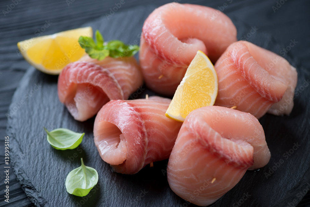 Close-up of marinated tilapia fillet rolls on a stone slate, selective focus Close-up of marinated tilapia fillet rolls on a stone slate, selective focus