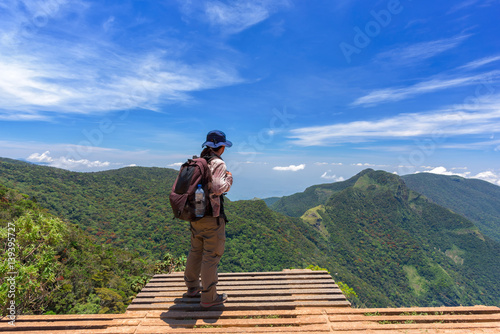 Man with hiking equipment walking in World's End within the Horton Plains National Park in Sri Lanka - success concept