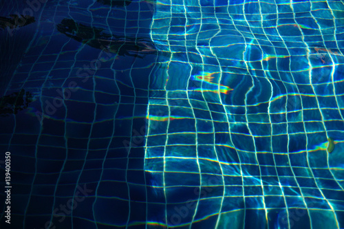 Blue pool water with sun reflections background