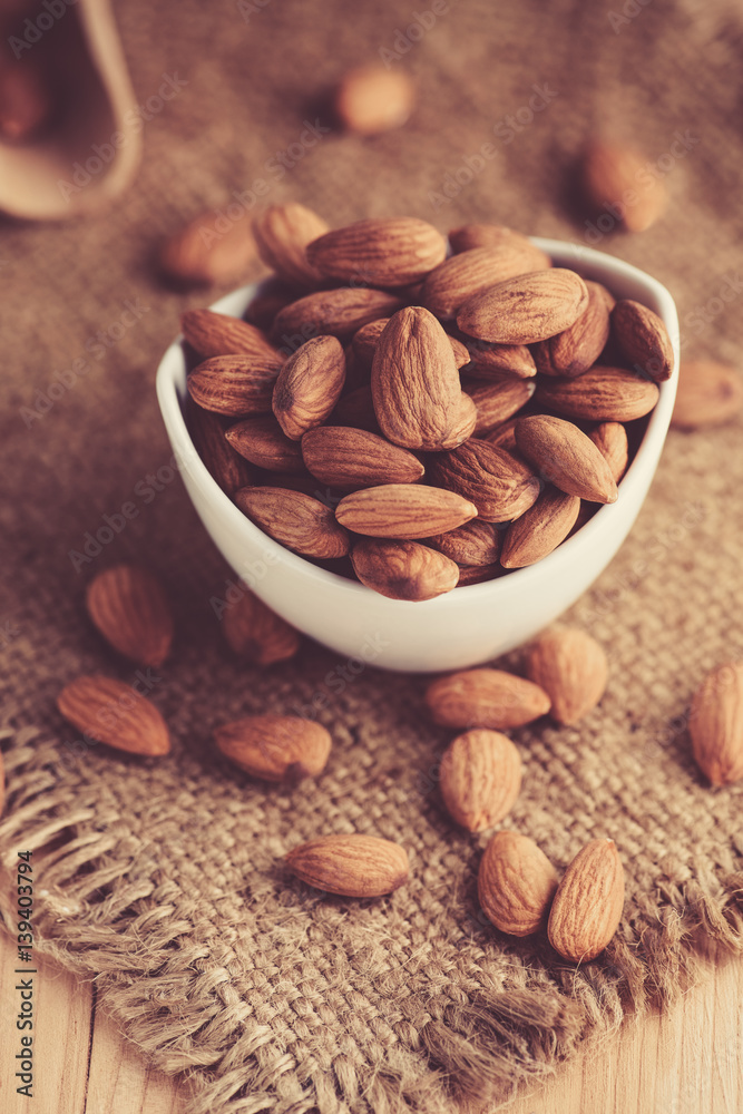 almonds in a ceramic bowl on sack background almonds in a ceramic bowl on sack background