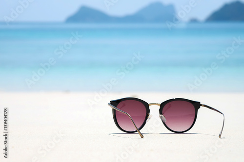 Fashion sunglasses on sea beach under clear blue sky. Summer holiday relax background with copy space.