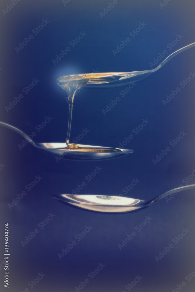 Honey pouring from spoon against a dark background