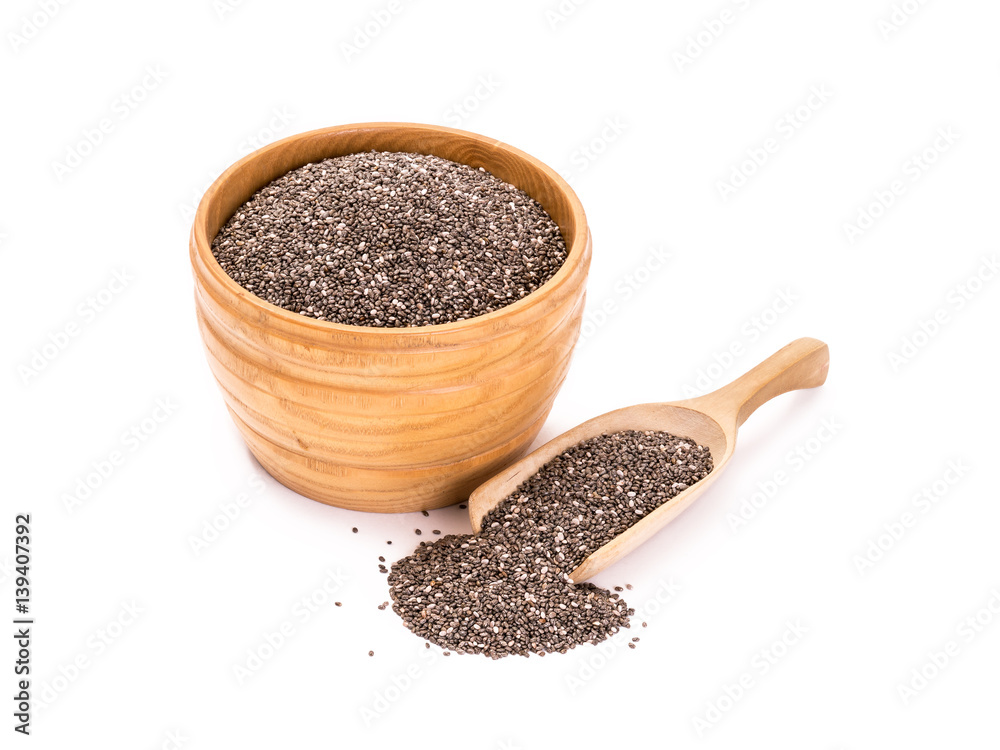 Wooden bowl with chia seeds and a spoon to the right of it on white background Wooden bowl with chia seeds and a spoon to the right of it on white background