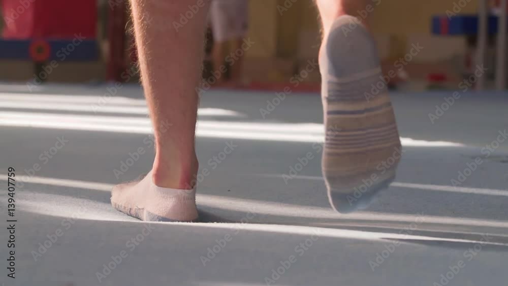 Male gymnast barefoot leg foots in socks walks on gymnastic mats