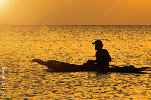 silhouette of fishermen in a boat. © noppharat