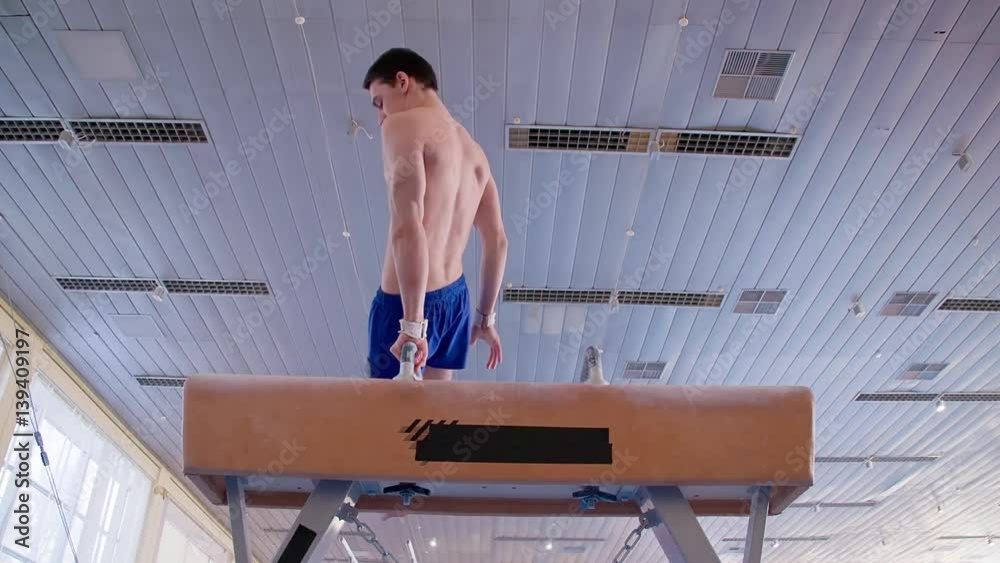 Young gymnast doing routine exercises on pommel horse HD slowmotion video. Olympics athlete
