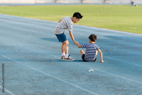 Boy help each other on blue track after fall