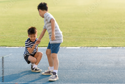 Boy help each other on blue track after fall