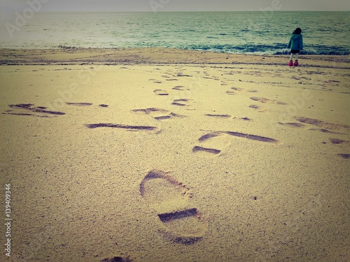 砂浜の足跡と海辺に佇む子供 Stock Photo Adobe Stock