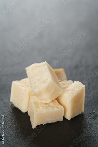 pieces of hard parmesan cheese on slate board, closeup photo