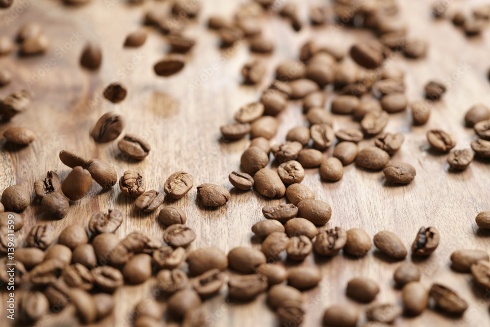 roasted coffee beans falling on wood table, shallow focus roasted coffee beans falling on wood table, shallow focus