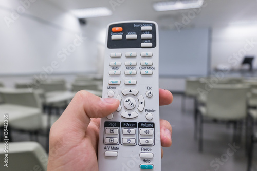 Holding remote control projector in hand in classroom