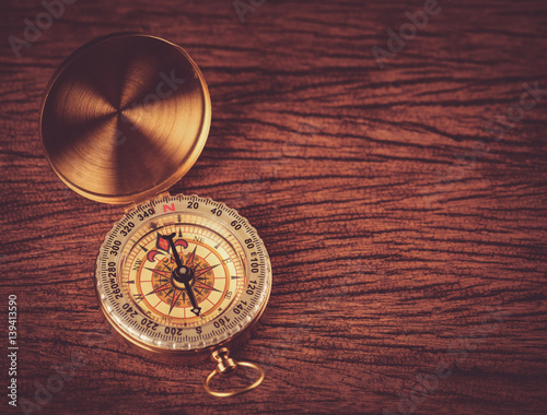 Old gold vintage compass on wood background