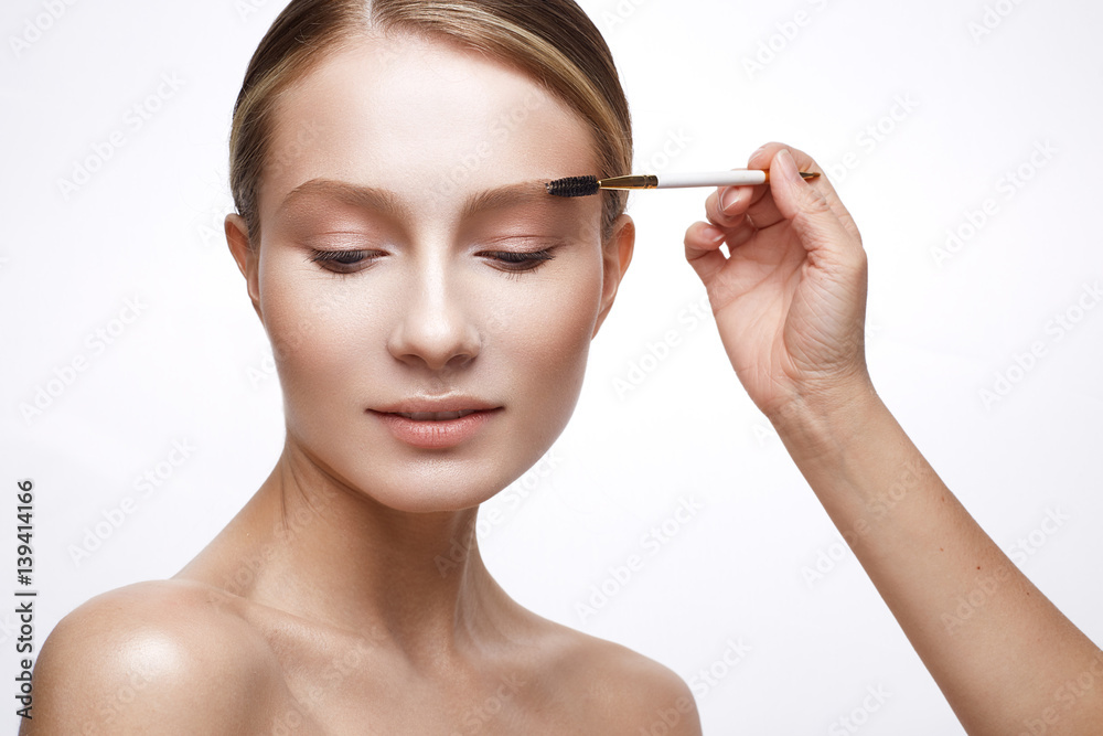 Young girl with a healthy skin and Nude makeup. Beautiful model on cosmetic procedures with a brush for applying makeup. The beauty of the face.