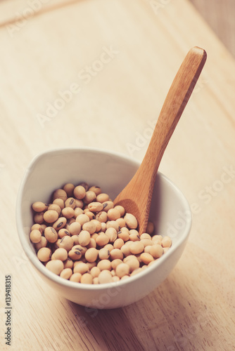 Soybeans in white ceramic bowl on wood block