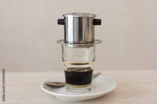 Traditional style Vietnamese coffee dripping in to a glass below with soft background and depth of field.