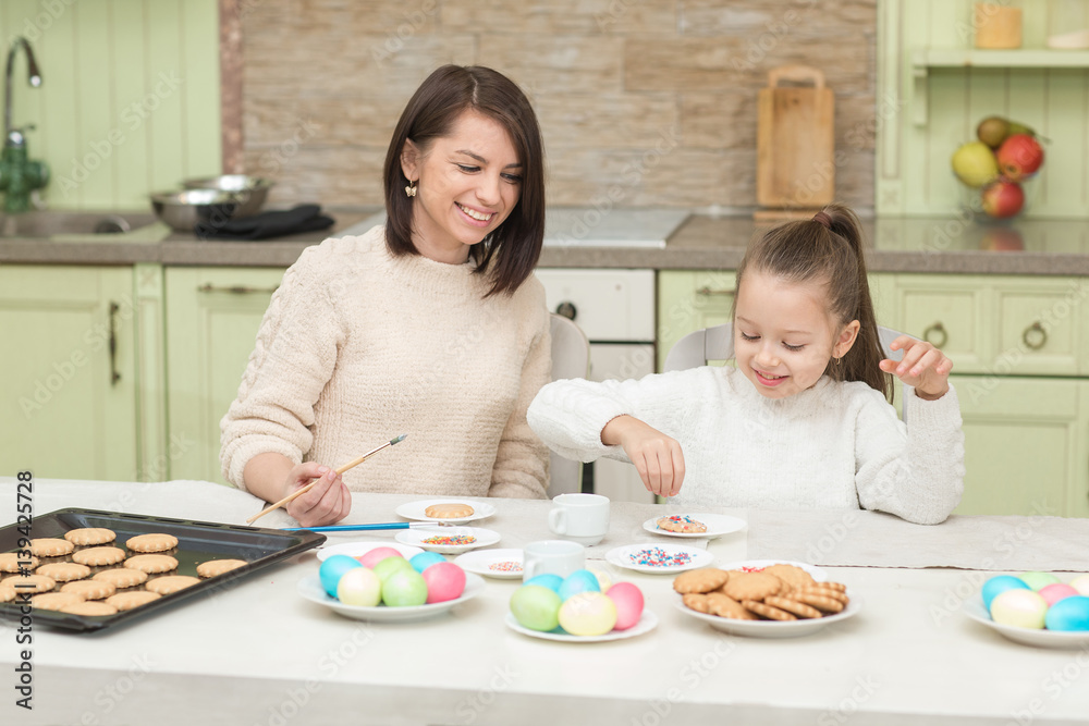 Mom and her daughter baking together and decorating the cookies Mom and her daughter baking together and decorating the cookies