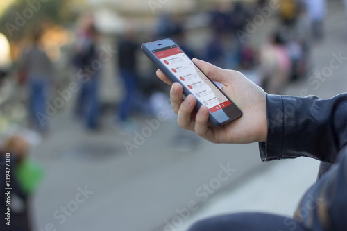 Side close up view of a man using the mobile phone in a turistic atmosphere. Inbox email on the screen