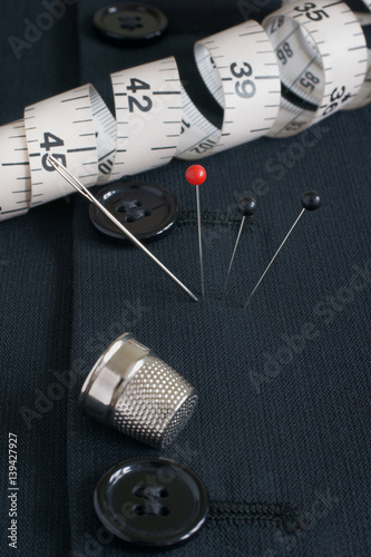 Black wool tuxedo fabric with tailors pins needle and thimble