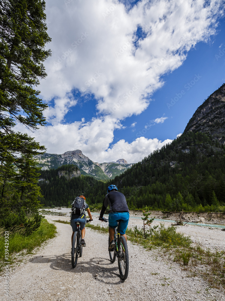 Mountain biking couple with bikes on track, Cortina d'Ampezzo, Dolomites, Italy