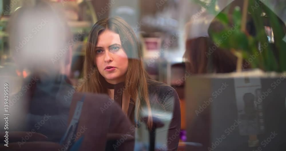 Young woman talks at cafe or restaurant HD video. View through glass window. Girls smiling and speaking Young woman talks at cafe or restaurant HD video. View through glass window. Girls smiling and speaking