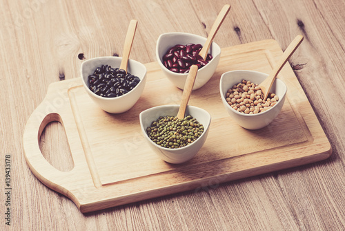 four colored beans in ceramic bowl on wood block