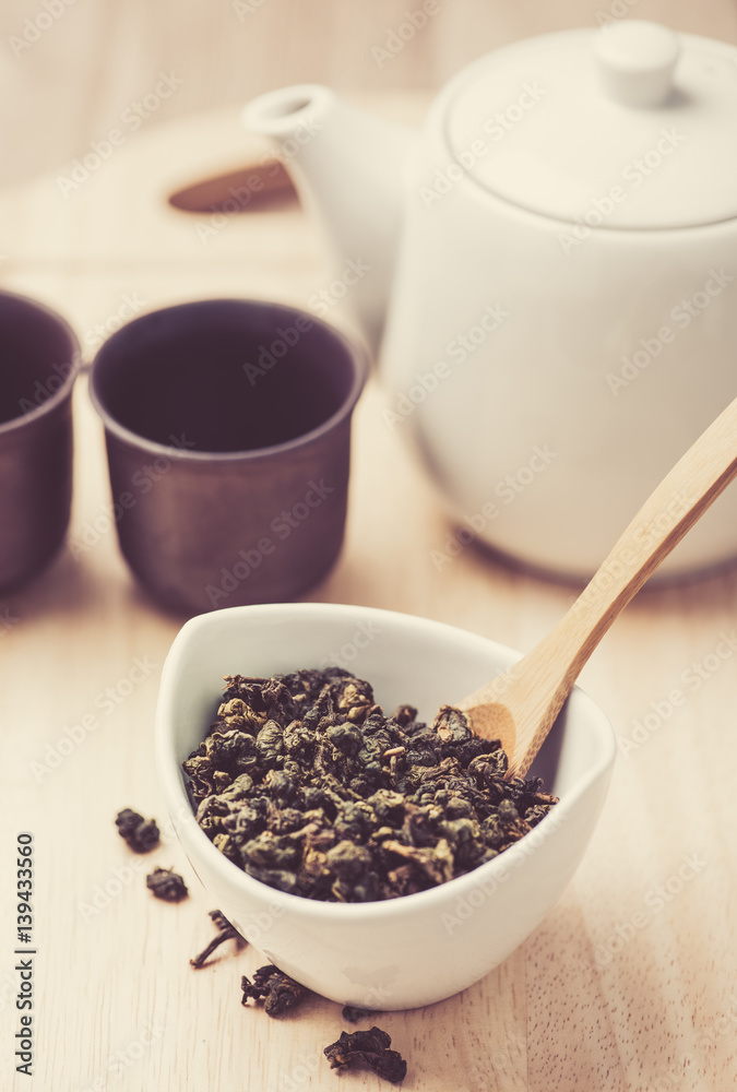 dry tea leaf in ceramic bowl wit whith pot on wood background dry tea leaf in ceramic bowl wit whith pot on wood background
