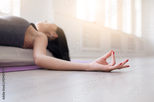 Beautiful young yoga girl lying in asana Shavasana